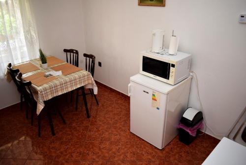 a kitchen with a table and a microwave on top of a refrigerator at Nóra apartman in Harkány