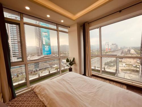 伊斯兰堡High Rise Presidential Suite in Elysium Opp Centaurus的一间卧室设有一张床和享有美景的大窗户
