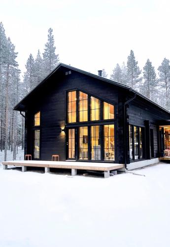 a black house with large windows in the snow at Black Work Levi Aarni in Kittilä