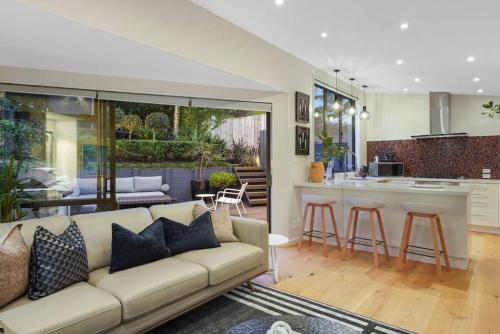 a living room with a couch and a kitchen at Elite Retreat Ponsonby with Parking and Deck in Auckland