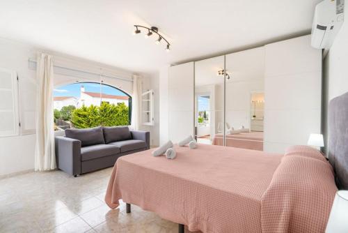 a bedroom with a large pink bed and a couch at S Olivera in Port d'Addaia