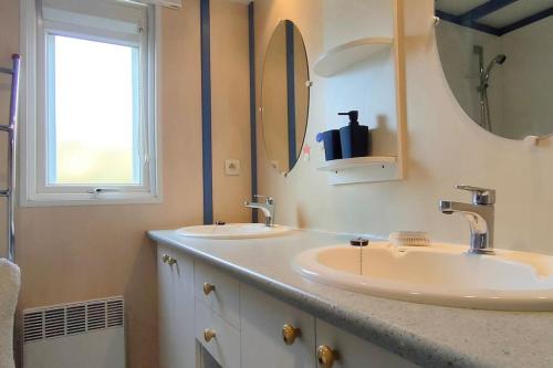 une salle de bain avec deux lavabos et un miroir dans l'établissement Chalet spacieux à 8 km de la mer, à LʼAiguillon-sur-Vie