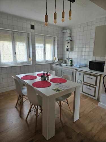 een keuken met een witte tafel en stoelen met rode matjes bij Apartamento rural in Pravia
