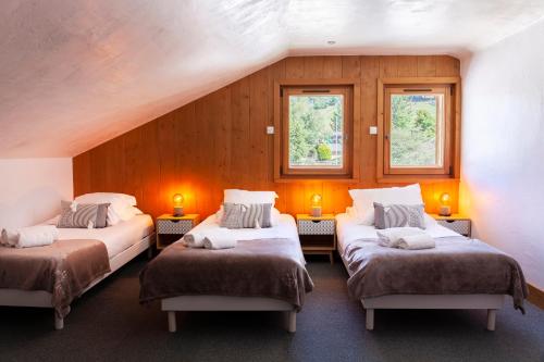 Cette chambre comprend trois lits et deux fenêtres. dans l'établissement Appartement Le Galetas des Planards, à Chamonix-Mont-Blanc