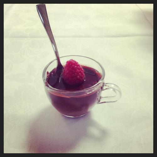 a cup of coffee with a raspberry on top at Hotel Kinda in Castiglione della Pescaia
