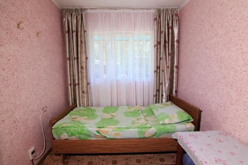 a small bedroom with a bed and a window at Nomads Home in Bishkek