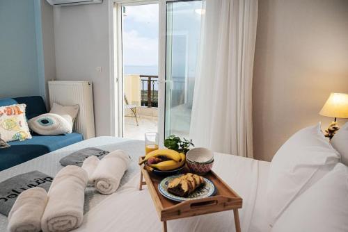 a bed with a plate of food on a table at Ammos Lux Apartments in Agia Triada