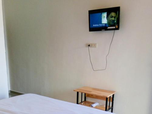 1 dormitorio con TV en la pared y mesa en RedDoorz @ Sihole Paradise Inn Parbaba en Sinapuran