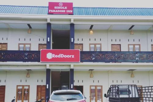 un edificio blanco con un letrero de puerta roja. en RedDoorz @ Sihole Paradise Inn Parbaba en Sinapuran