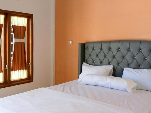 Un dormitorio con una cama con almohadas blancas y una ventana en RedDoorz @ Sihole Paradise Inn Parbaba en Sinapuran