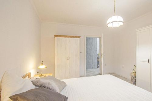 a white bedroom with a large bed and a lamp at Apartmán 2kk Zlámanka in Kroměříž
