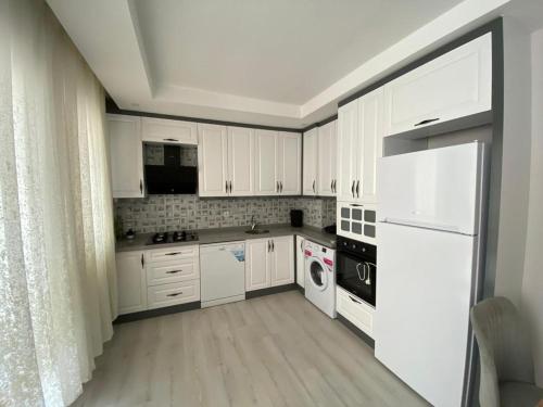 una cocina blanca con armarios y electrodomésticos blancos en 2+1 MUHTEŞEM TATİL EVİ en Dalaman