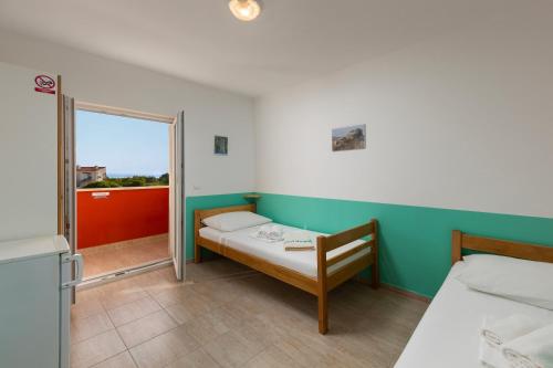 a small room with two beds and a window at Hostel & Rooms Vagabundo in Novalja