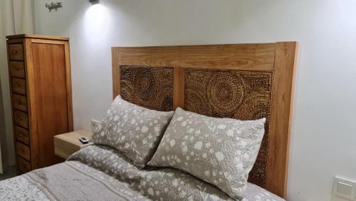 un letto con testiera in legno e 2 cuscini di TREBOL Apartamentos Benalmádena ad Arroyo de la Miel