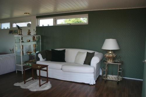 a living room with a white couch and green wallpaper at Falsterly Glamping in Horbelöv