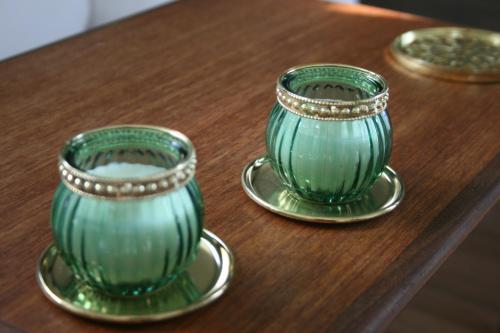 Duas chávenas de vidro verdes sentadas numa mesa de madeira em Falsterly Glamping em Horbelöv