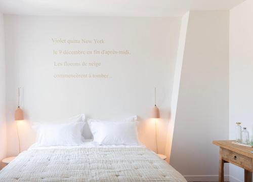 a bedroom with a white bed with white pillows at La Bâtisse en Blanc in Golfe-Juan