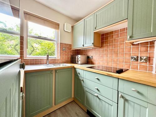 eine Küche mit grünen Schränken und einem Fenster in der Unterkunft Cherry Blossom Cottage in York