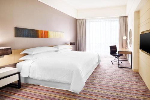 a hotel room with a white bed and a television at Four Points by Sheraton Puchong in Puchong