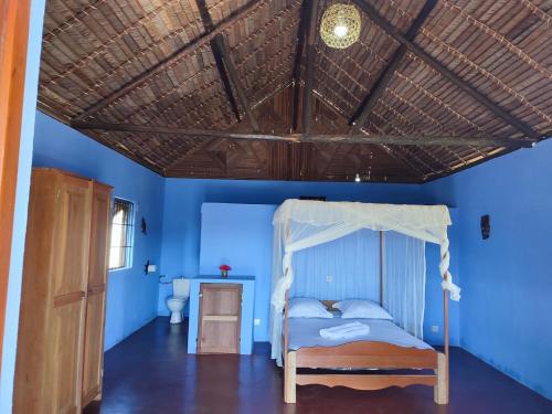 una camera con letto e soffitto in legno di Auberge Le Lagon a Nosy Be