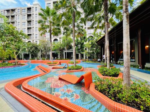 a swimming pool with orange chairs and palm trees at Nara lahabana in Hua Hin