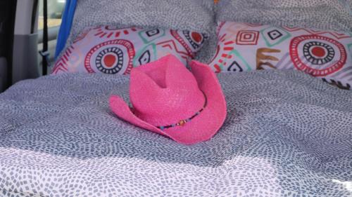 un sombrero rosa sentado en la parte superior de una cama en EndlessCamperVan, en San Miguel de Abona