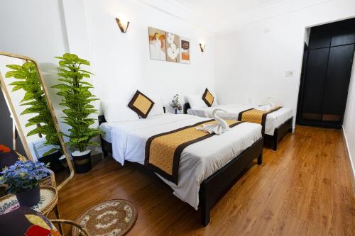 two beds in a room with white walls and wooden floors at Casablanca Hotel in Hue