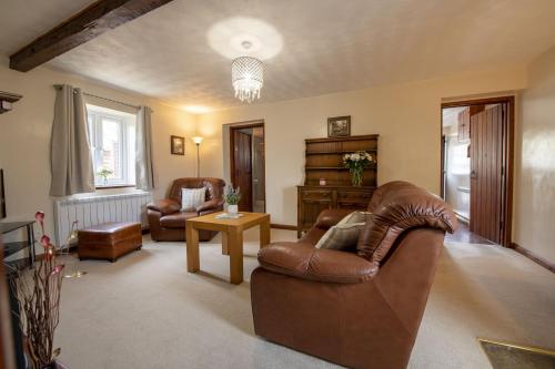 a living room with two leather chairs and a table at Corner Cottage in Leyburn