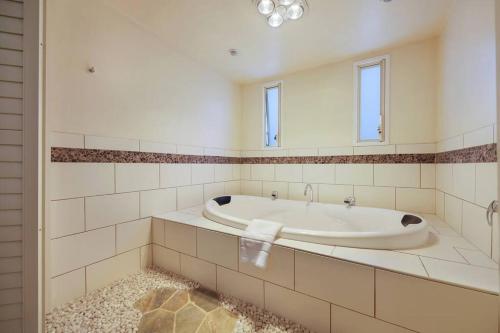 uma casa de banho branca com uma banheira e um espelho. em Logans Beach Apartments - BeachHouse em Warrnambool