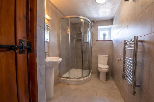 a bathroom with a shower and a toilet and a sink at Corner Cottage in Leyburn