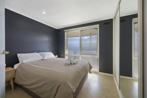 a bedroom with a bed and a window at Logans Beach Apartments - BeachHouse in Warrnambool