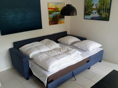uma cama azul com lençóis brancos e almofadas em Airbnb-lejligheder, Villerslev 