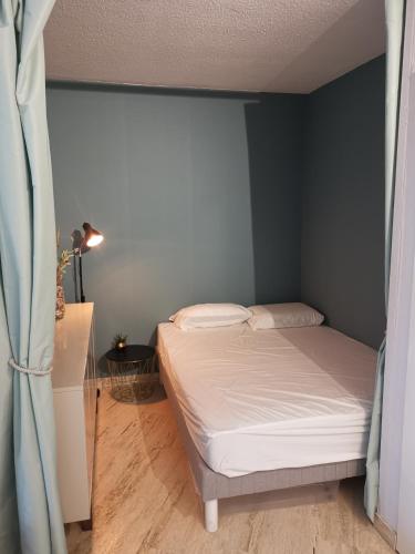 Cette petite chambre comprend un lit avec des draps blancs. dans l'établissement Appartement au calme (2 à 4 Pers.) avec Piscines + Parking, à Mandelieu-la-Napoule
