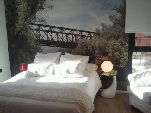 LOS PUENTES casa con jacuzzi para 2 في Olmos de Peñafiel: غرفة نوم بسرير مع لوحة على جسر