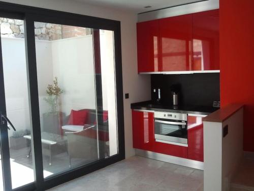 a kitchen with red cabinets and a glass door at LOS PUENTES casa con jacuzzi para 2 in Olmos de Peñafiel