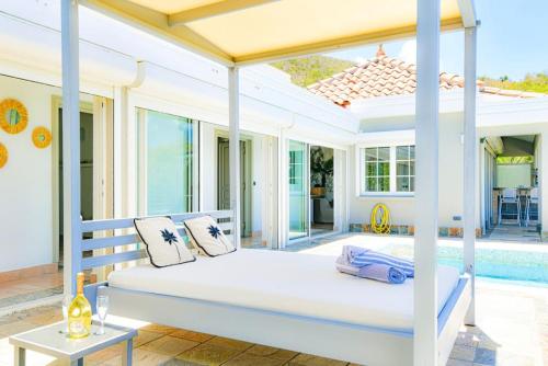 un lit blanc sur un porche avec une piscine dans l'établissement Villa Caraibe Sea 5 min walk to Orient Bay beach, à La Baie-Orientale