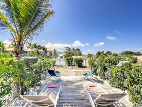 a deck with chairs and a palm tree at Maison Caraibes beach front on Orient Bay with 2 big pools in Orient Bay