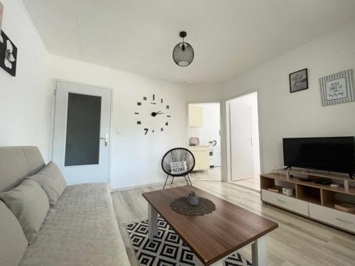 Starlux apartment في موستار: غرفة معيشة مع أريكة وساعة على الحائط