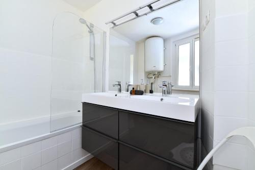 a white bathroom with a sink and a shower at Appartement Les Cigognes du Centre in Colmar