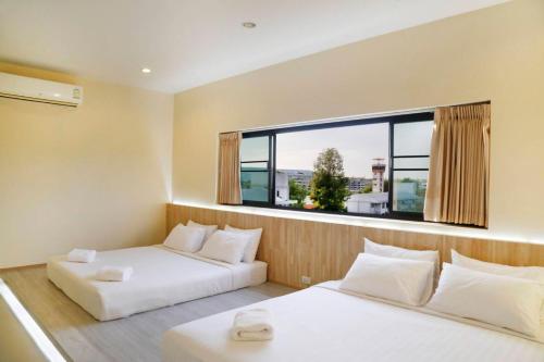 two beds in a room with a large window at STAYHERE@AIRPORT SERVICE APARTMENT in Ban Bo Han