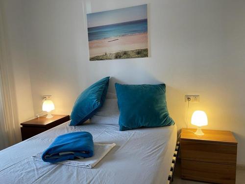 Apartamento en el centro de Miami Platja 155B - INMO22 في هوسبيتاليت دي لانفنت: غرفة نوم بسرير ومخدات زرقاء ومصباحين