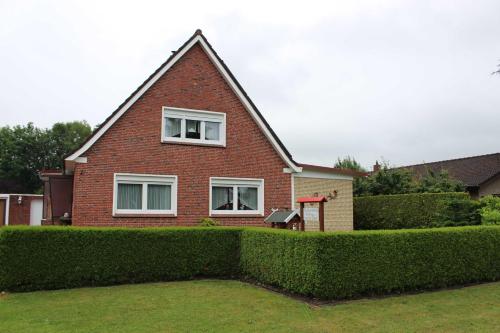 ein Haus mit einer Hecke davor in der Unterkunft Ferienwohnung Drieling, 85091 in Ostrhauderfehn