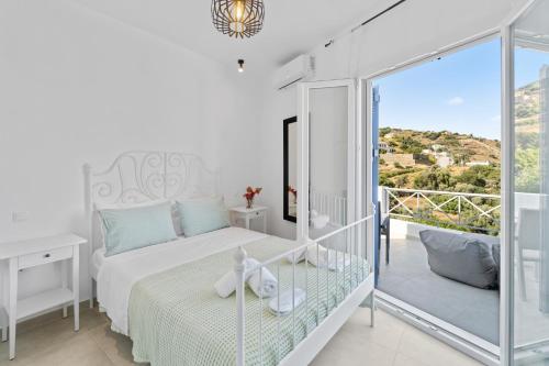 a white bedroom with a bed and a balcony at Seaside & Modern Flats by Explore Andros in Steniaí