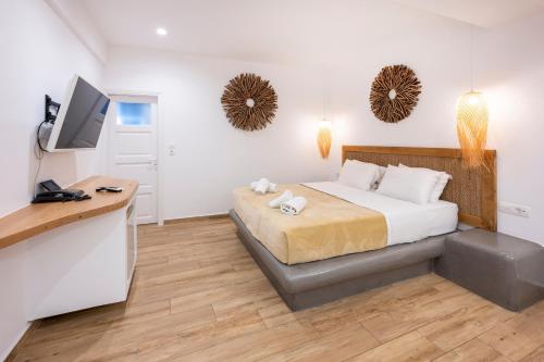 a bedroom with a bed and a desk with a television at Smy Mediterranean White Santorini in Kamari