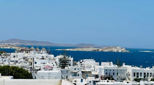 a view of a city with white buildings and the ocean at Mykonian Starling - Town n' Sunset View Apartment in Mýkonos City