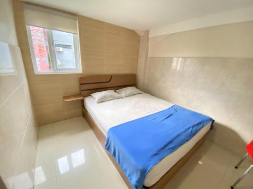 una piccola camera da letto con un letto con una coperta blu di Penginapan Star Ambon Mitra RedDoorz a Ambon