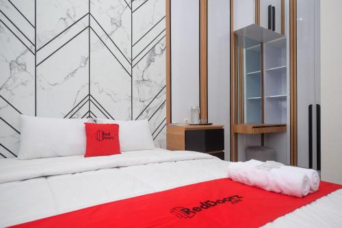 a bedroom with a white bed with a red blanket at RedDoorz at Tasneem Puspowarno Semarang in Kalibanteng-lor