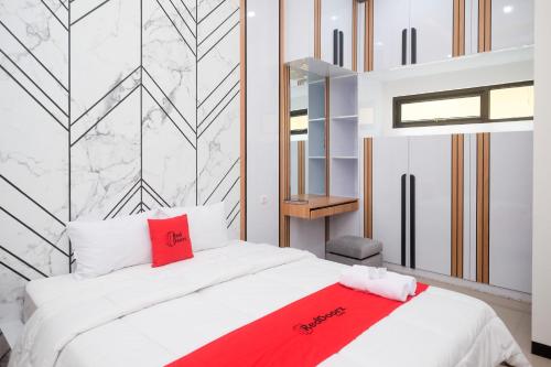 - une chambre avec un lit blanc et une couverture rouge dans l'établissement RedDoorz Syariah at Tasneem Puspowarno Semarang, à Kalibanteng-lor