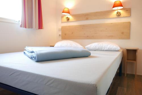 a bed in a room with two pillows on it at CityKamp Lyon in Dardilly