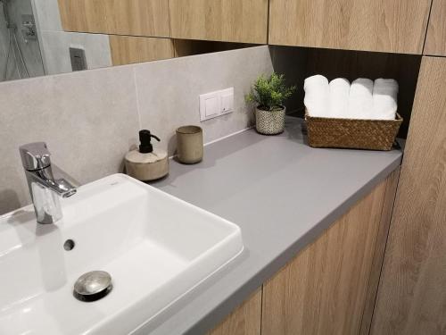 a bathroom counter with a sink and a basket of towels at Apartament Nałęczowski Zakątek in Nałęczów